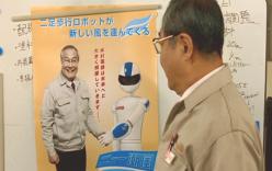 ホワイトボードにポスターを貼る木村電気社長