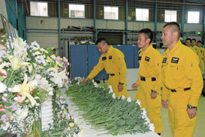 県防災航空センターの格納庫に設けられた献花台には次々と白い菊の花が供えられた＝川島町で